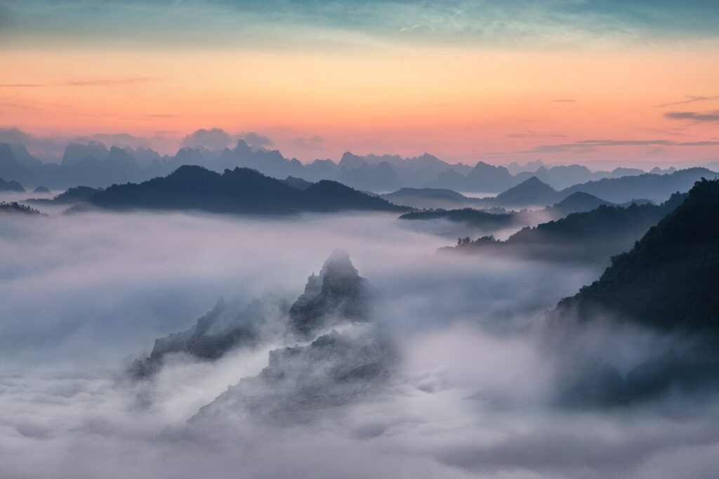 Mountain landscape partially covered in fog and mist, creating a calm and reflective atmosphere